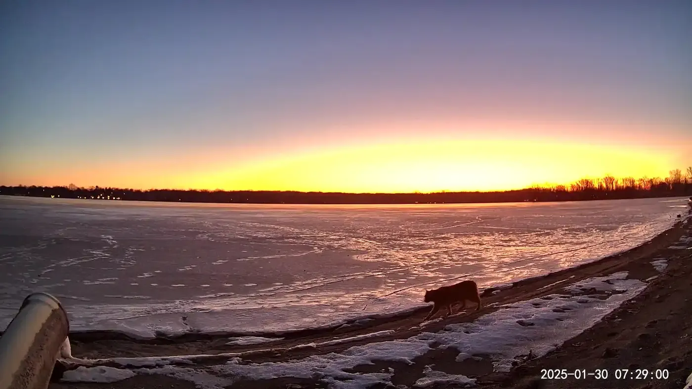 Winona Lake frozen over at sunrise, seen from the shoreline